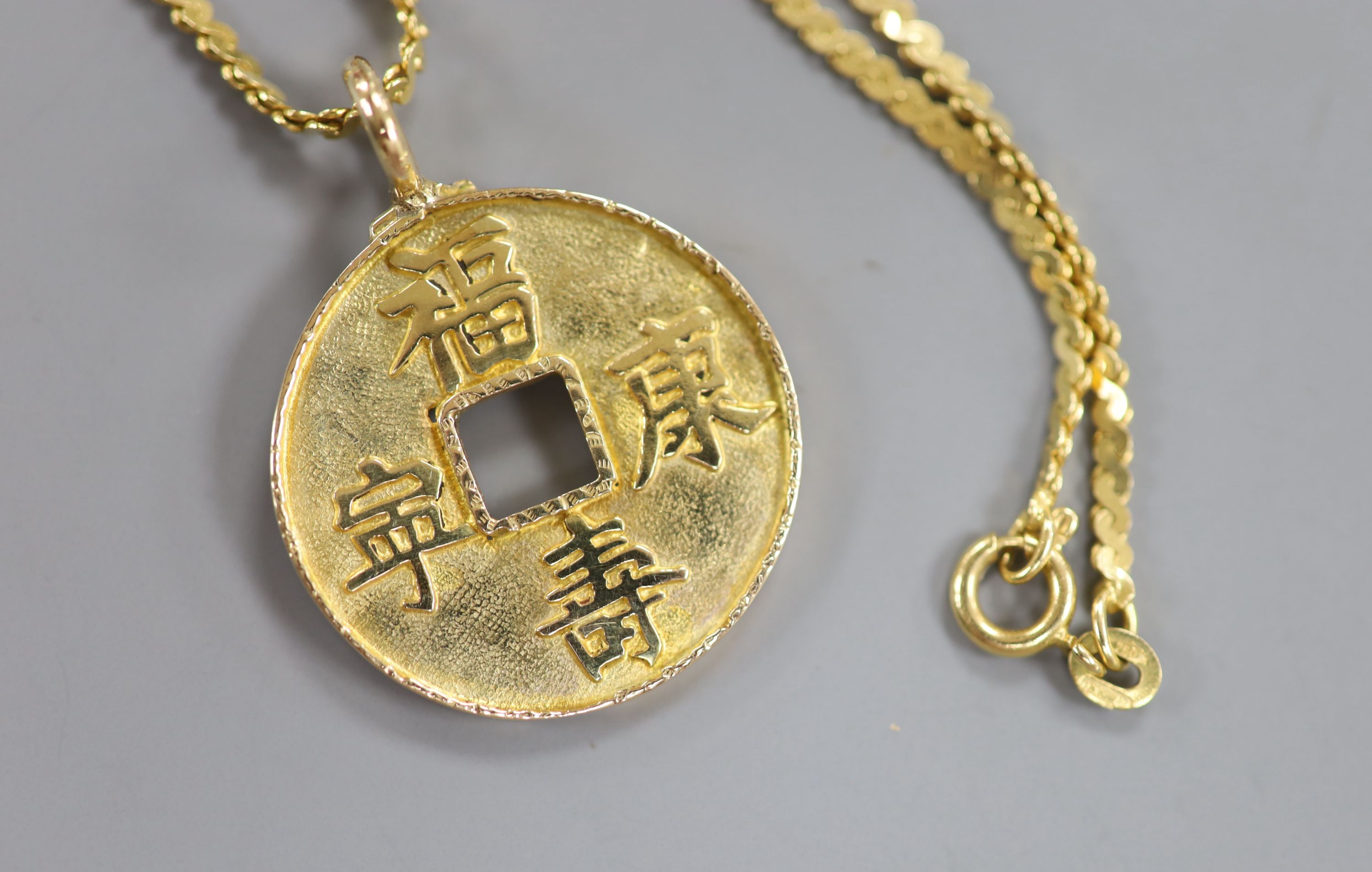 A Chinese yellow metal amulet, on an Italian Uno-A-Erre 750 chain, gross 13 grams.
